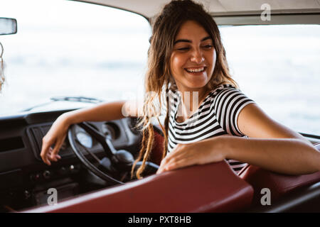 young woman driver smiling and look back on road trip Stock Photo