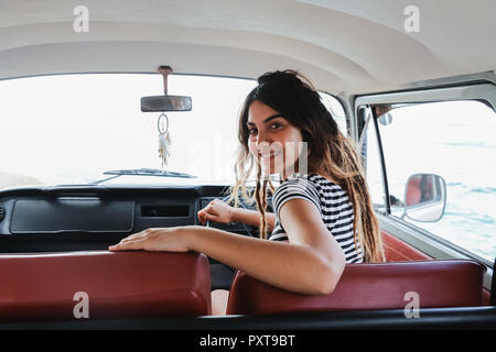 young woman driver smiling and look back on road trip Stock Photo