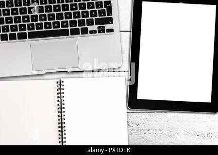 laptop, tablet computer and spiral notepad on rustic white wooden table Stock Photo