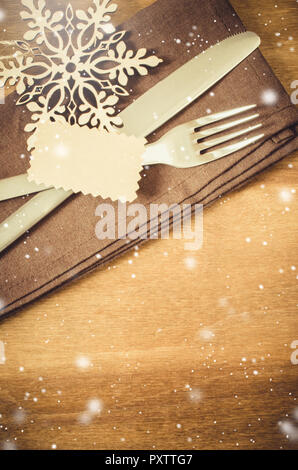 Winter Table Setting. Silverware with Empty Tag and Linen Napkin on Rustic Wooden Background. Top View. Copy Space. Snow Effect. Toned Image. Selectiv Stock Photo