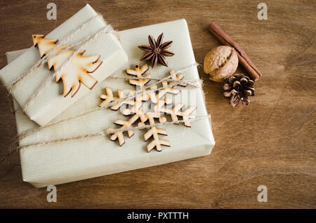 Christmas Gift Boxes in Rustic style Decorated with Wooden Snowflake and Christmas Tree, Jute on Wooden Background. Selective Focus. Top View. Stock Photo