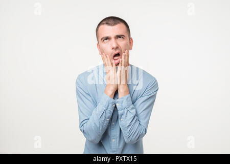 Young caucasian man in blue shirt tired sleepy. Stock Photo