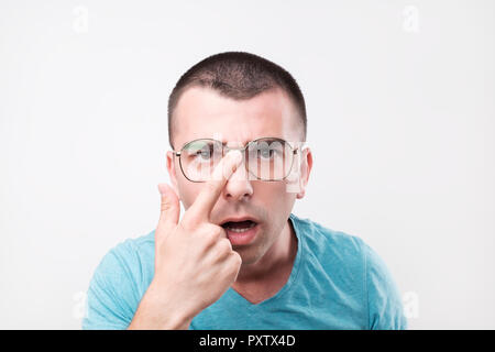Young handsome man in glasses thinking in doubts and touching lips on gray. Stock Photo