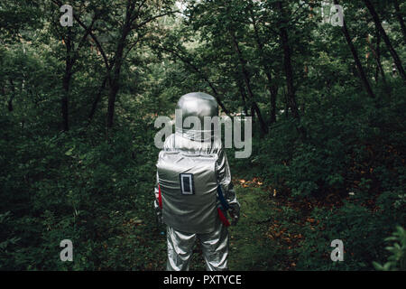 Spaceman exploring nature, walking in forest Stock Photo