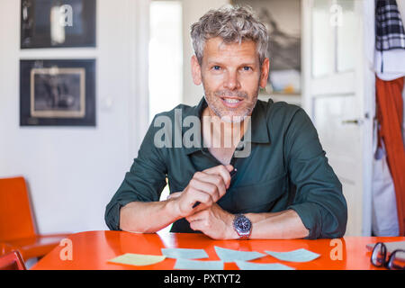 Portrait of mature man sitting at table with notepads Stock Photo
