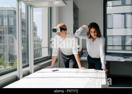 Two architects working on blueprints, man using VR glasses Stock Photo