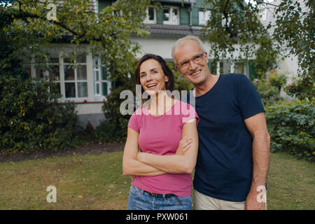 Happy mature couple standing in garden of their home Stock Photo