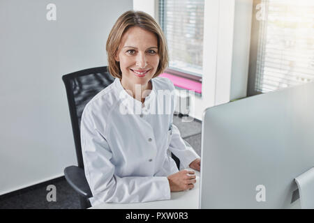 Female doctor working on computer, smiling Stock Photo