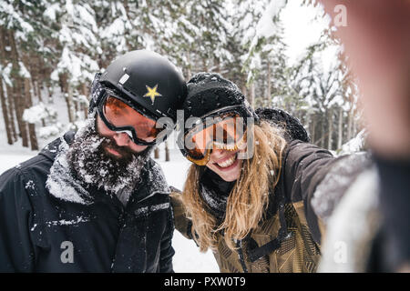 Selfie of smiling couple in skiwear in winter forest Stock Photo