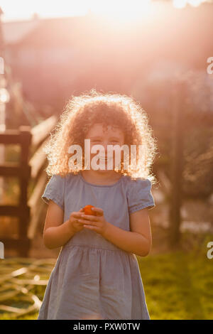 Portrait of little girl standing at backlight in the garden Stock Photo