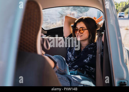 Smiling young woman wearing sunglasses sitting in a car Stock Photo
