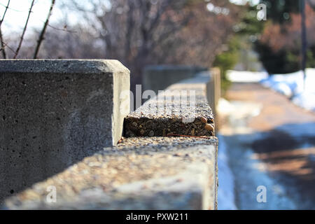 The edge of a cement wall along a footpath in winter Stock Photo