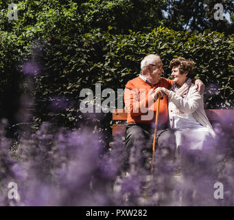 Senior couple sitting on bench in a park, falling in love Stock Photo