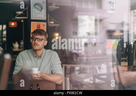 Young business owner sitting in his coffee shop, drinking coffee Stock Photo