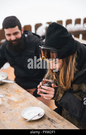 Couple in skiwear having a hot drink at mountain lodge Stock Photo