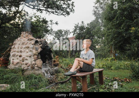 Boy relaxing on wooden bench in the garden