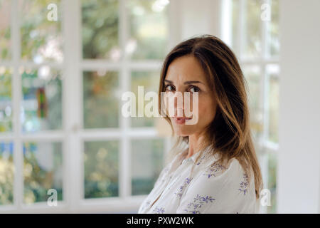 Portrait of serious mature brunette woman at the window Stock Photo