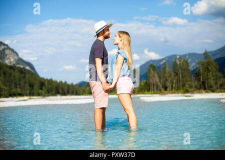 Young couple standing in water, holding hands Stock Photo