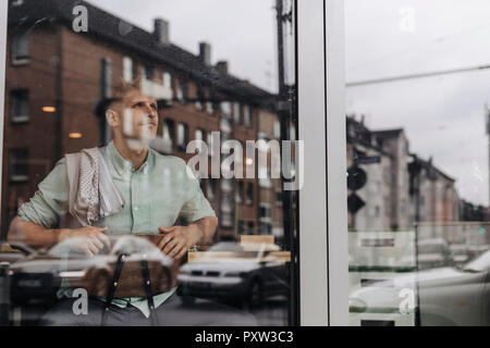 Young business owner sitting in his coffee shop, daydreaming Stock Photo