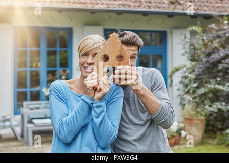 Portrait of smiling couple standing in front of their home holding house model Stock Photo