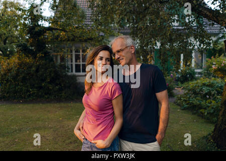 Smiling mature couple standing in garden of their home Stock Photo
