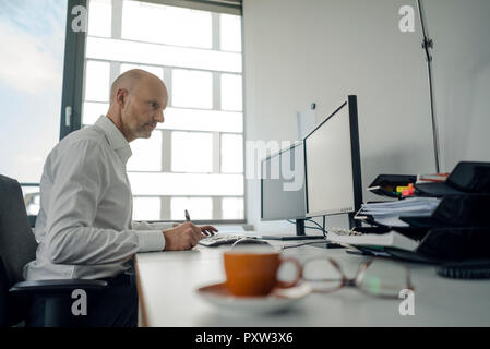 Businessman working on his computer, taking notes Stock Photo