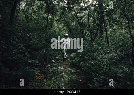 Spaceman exploring nature, looking at plants in forest Stock Photo