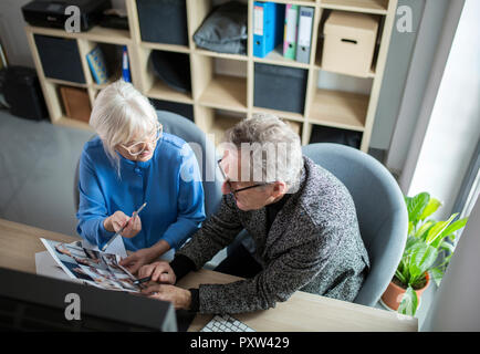 Two senior colleagues working together at desk in office discussing photos Stock Photo