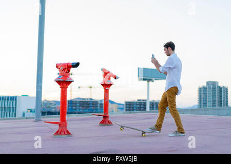 Young man with a skateboard using cell phone Stock Photo
