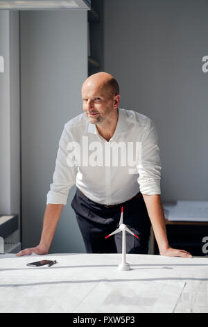 Engineer working in his office with model of a wind wheel on his desk Stock Photo