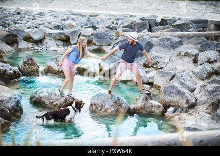 Young couple crossing river Stock Photo