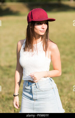 Young woman wearing baseball cap standing on a meadow Stock Photo