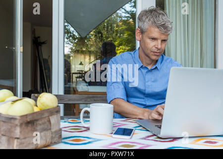 Portrait of mature man using laptop on terrace Stock Photo