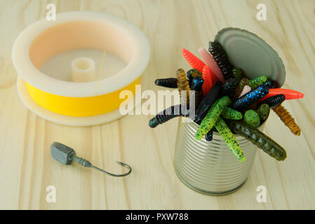 Tin can of colourful artificial plastic worms with yellow fishing line and lead jig head hook Stock Photo