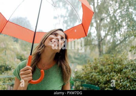 Smiling mature woman standing in rain under umbrella