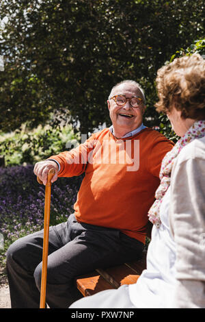 Senior couple sitting on bench in a park, talking Stock Photo