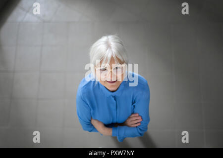 Smiling senior businesswoman looking up on office hallway Stock Photo