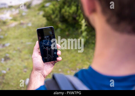 Austria, Tyrol, Hiker using compass app at Lake Seebensee Stock Photo