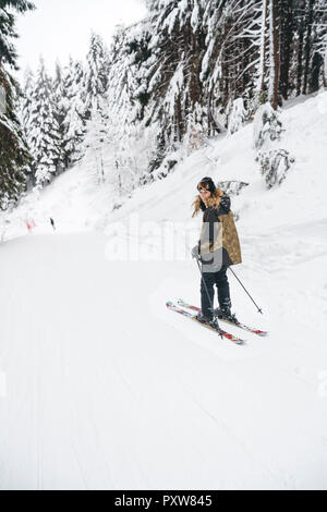 Portrait of happy young woman skiing in winter forest Stock Photo