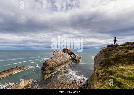 UK, Scotland, Portknockie, tourist at Bow Fiddle Rock natural arch Stock Photo