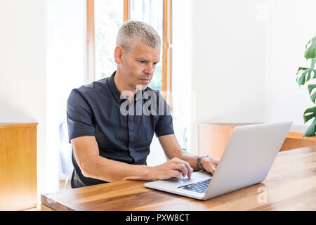 Mature man using laptop on wooden table Stock Photo
