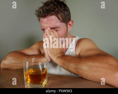 young wasted and depressed alcohol addict man in singlet drinking glass of whiskey feeling desperate suffering alcoholism problem booze addiction Stock Photo