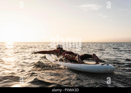 Young man on paddleboard at sunset Stock Photo