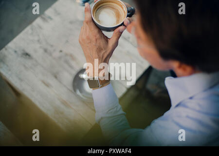 Mature businessman sitting in coffee shop, wearing smart watch Stock Photo