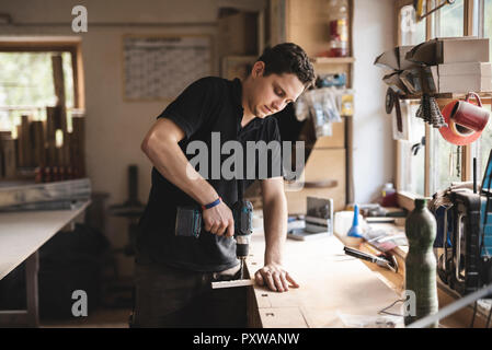 Carpenter using drill on piece of wood in workshop Stock Photo