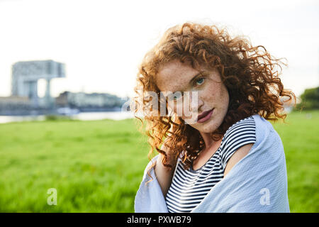 Germany, Cologne, portrait of redheaded freckled young woman Stock Photo