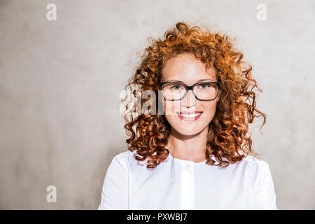 Germany, Cologne, portrait of freckled young woman wearing glasses Stock Photo