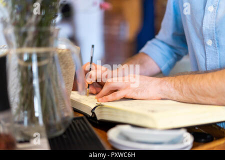 Close-up of man writing in notebook Stock Photo