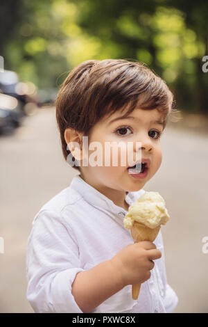 Portrait of toddler with vanilla ice cream cone in park Stock Photo