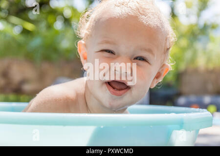 Boy sitting in baby bathtub Stock Photo